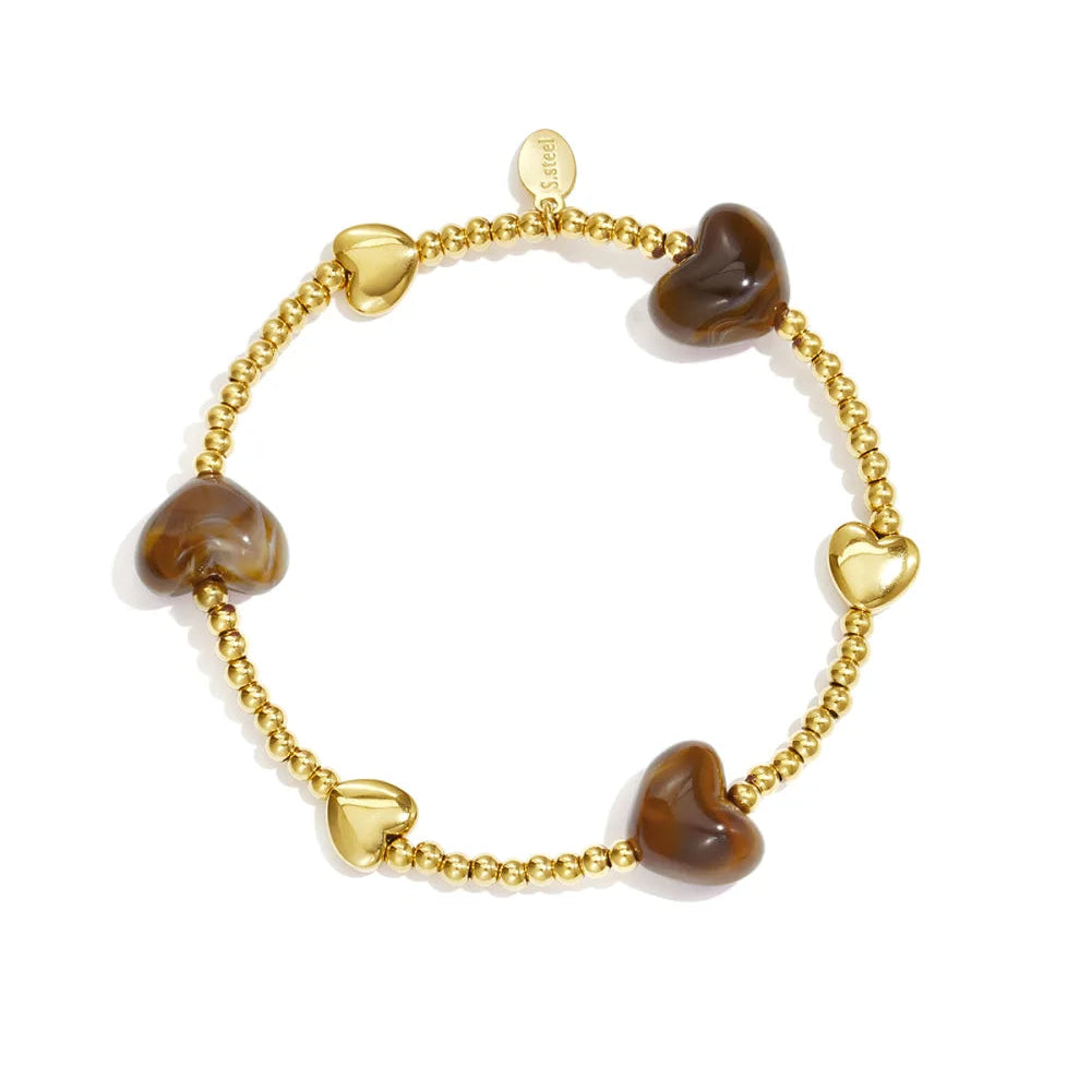 Goudkleurige stretch armband met bruine kraaltjes in hartvorm, witte achtergrond