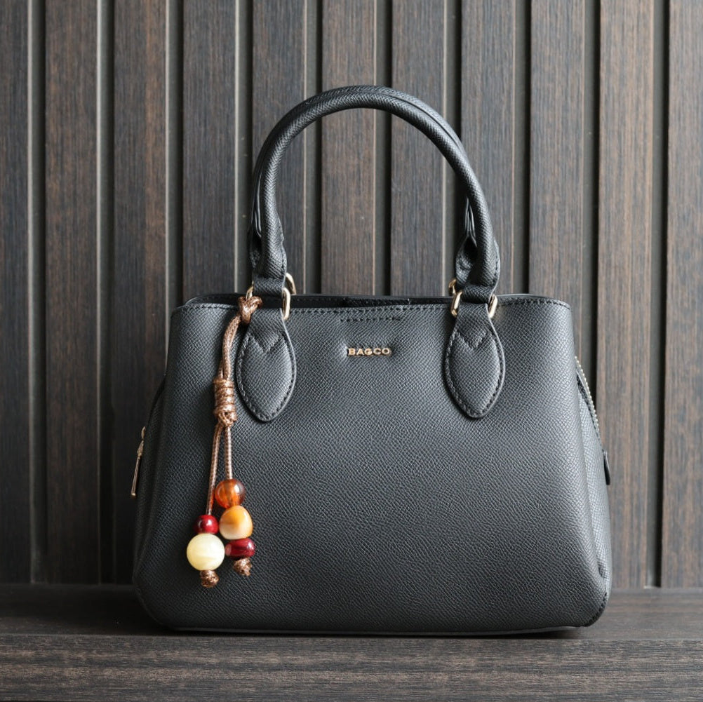 Handtas Bagco kleur zwart, met bagcharm op donkere achtergrond