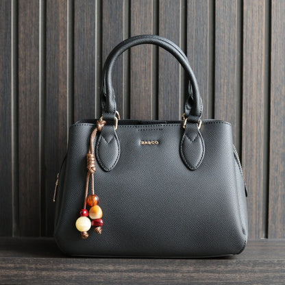 Handtas Bagco kleur zwart, met bagcharm op donkere achtergrond